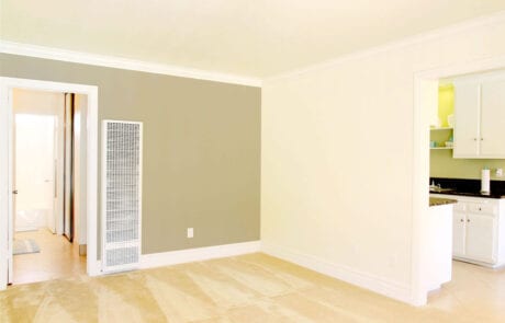 13-Unit1LR-1 Apartments in Tustin - Las Casas Apartments - Living Room Area With Cozy Carpet, Air Conditioning Unit, and Stylish Accent Wall